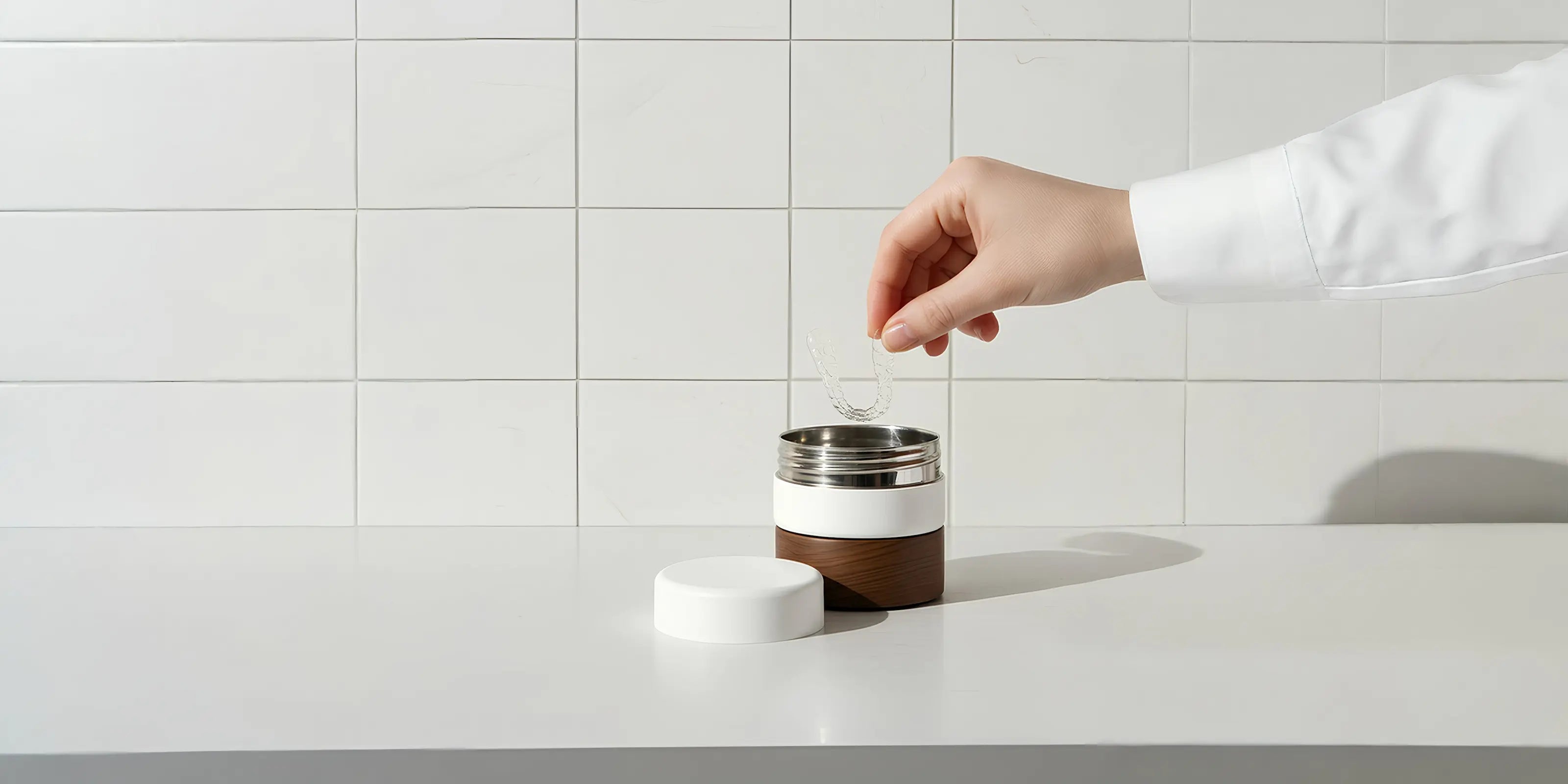 Hand holding a white and brown thermos against a tiled wall background